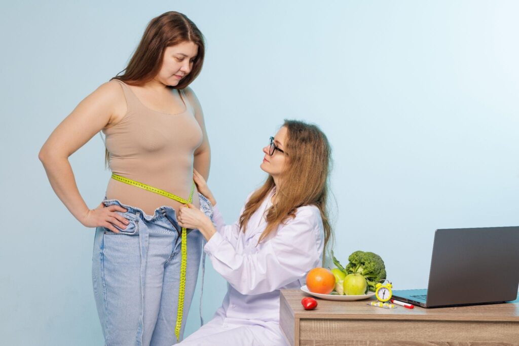 Female weight loss specialist measuring a woman's waist during a metabolic reset consultation. Concept of natural weight loss support and personalized fat loss coaching.