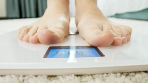 Person standing on scale tracking progress of weight loss journey