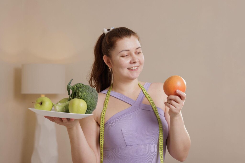 Smiling woman holding healthy food and grapefruit after starting a natural weight loss service focused on real foods.
