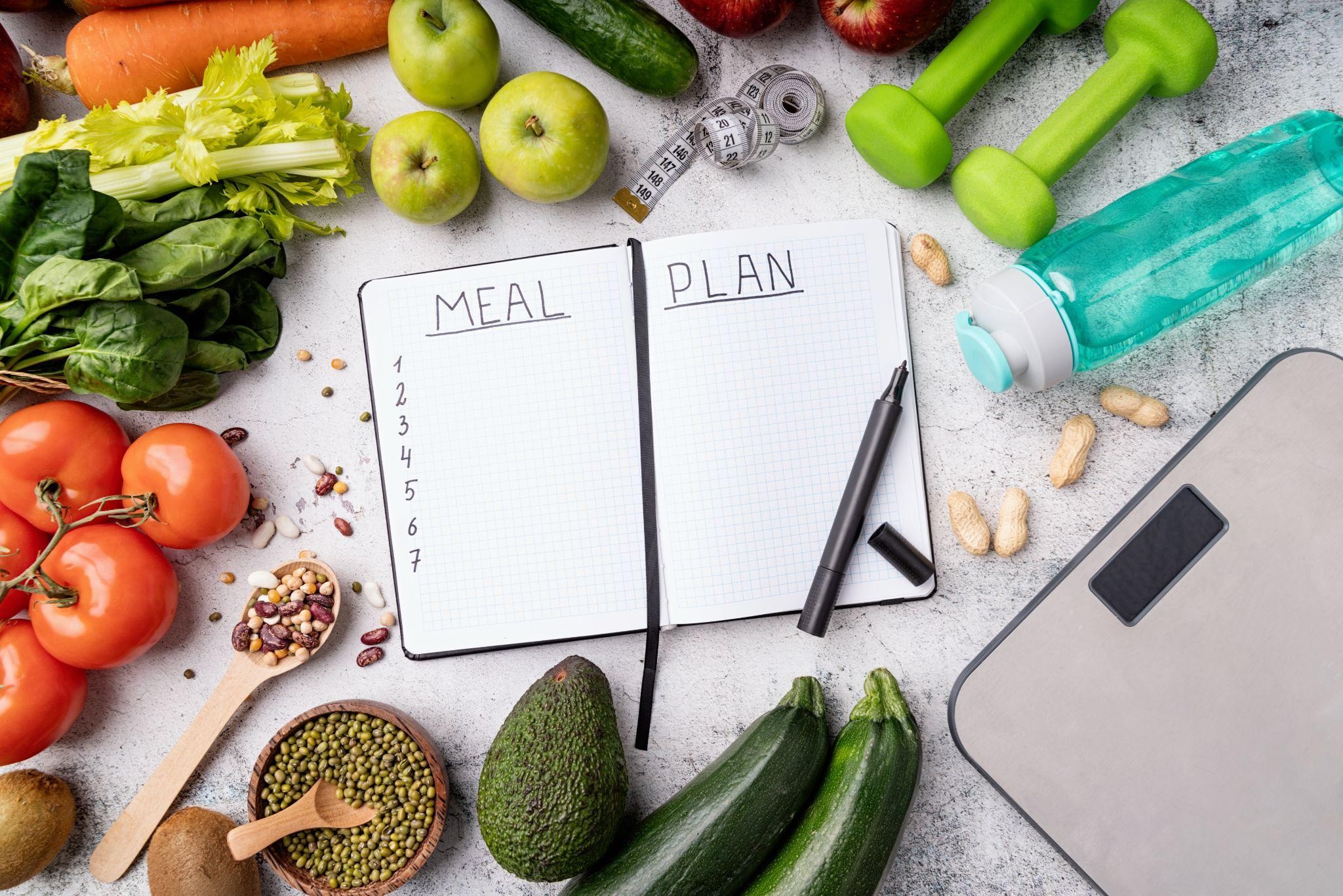 Open meal planning notebook surrounded by fresh fruits, vegetables, and healthy foods — illustrating simple meal planning ideas for busy parents focused on sustainable weight loss.